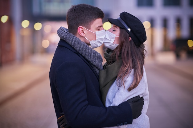 Feliz pareja celebrando el día de San Valentín en máscaras durante la pandemia de covid-19 en la ciudad