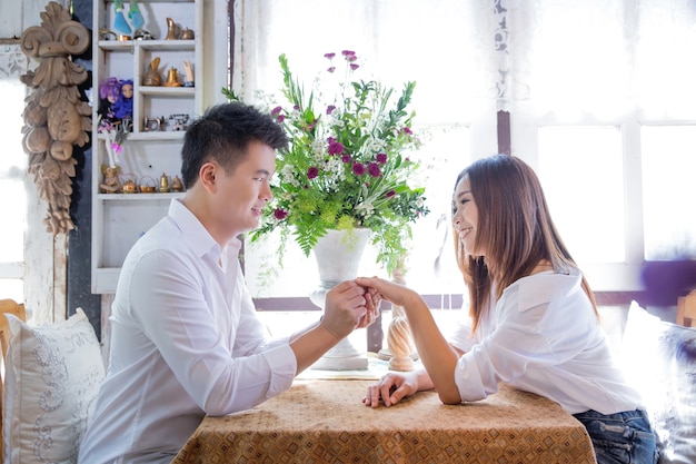 Feliz pareja de citas y coqueteando y tomados de la mano juntos en el restaurante