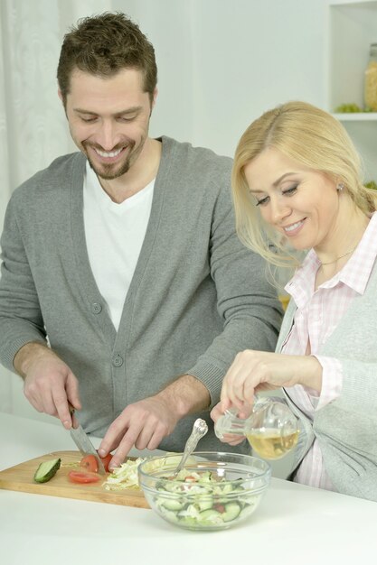 Feliz pareja cocinando en la cocina de casa