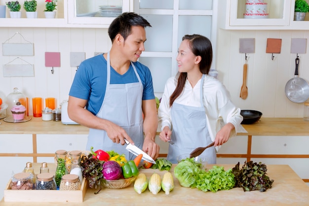 Feliz pareja cocinando juntos, pareja preparando ensalada con ingredientes frescos
