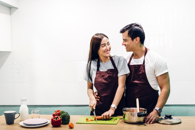 Feliz pareja cocinar y preparar comida juntos en la cocina