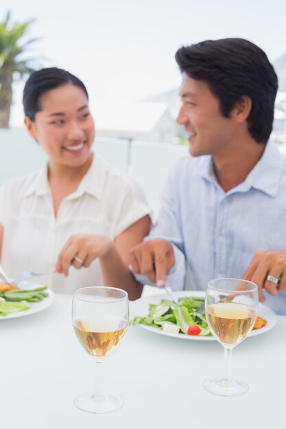 Feliz pareja con una comida junto con vino blanco