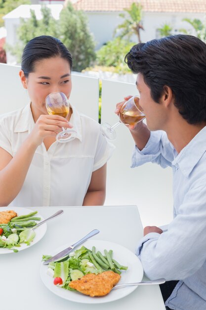 Feliz pareja con una comida junto con vino blanco