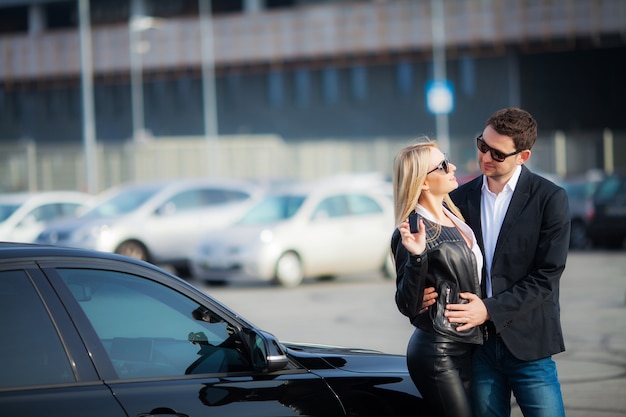 Feliz pareja compra nuevo coche negro moderno