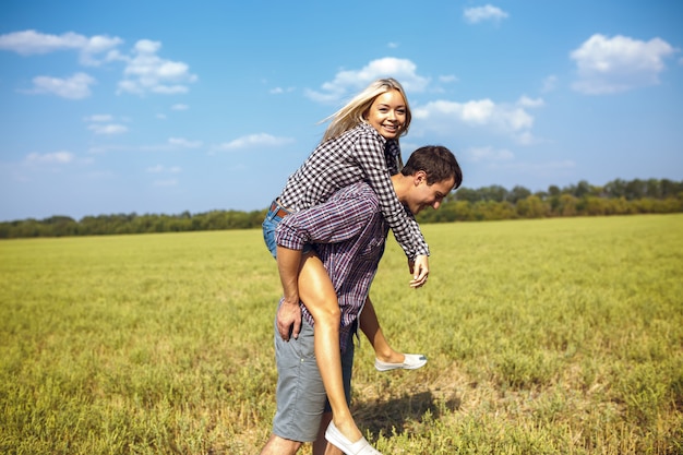 Feliz pareja corre juntos en campo verde mientras sostiene globos rojos