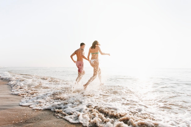 Feliz pareja corriendo en el agua