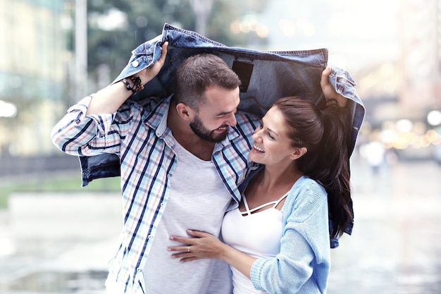 feliz pareja corriendo bajo la lluvia en la ciudad