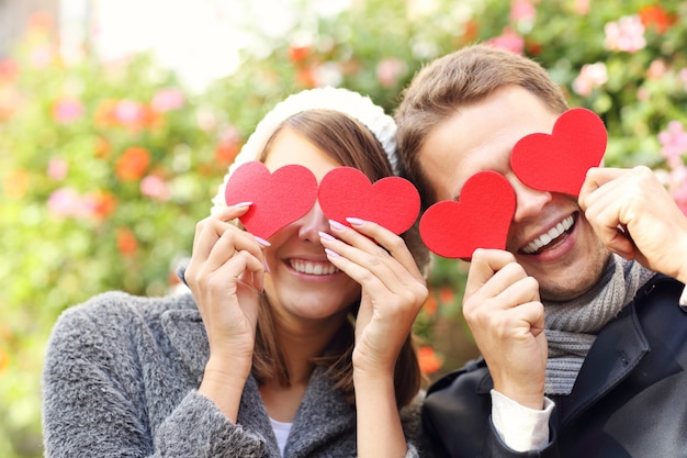 feliz pareja cubriéndose los ojos con corazones