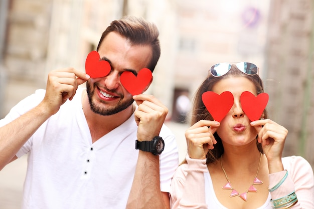 feliz pareja cubriéndose los ojos con corazones