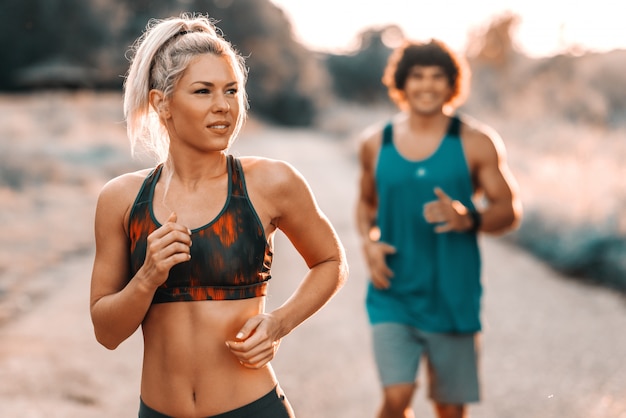 Feliz pareja deportiva preparándose para el maratón en la naturaleza. Día soleado de verano, enfoque selectivo en la mujer.