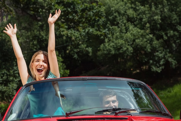 Feliz pareja divirtiéndose en su cabriolet rojo