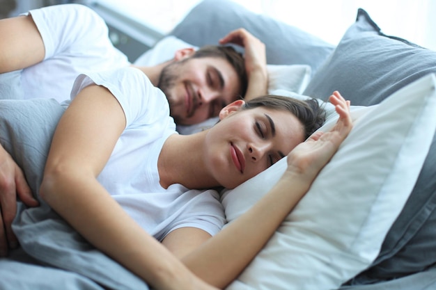 Feliz pareja durmiendo en una cómoda cama en casa.