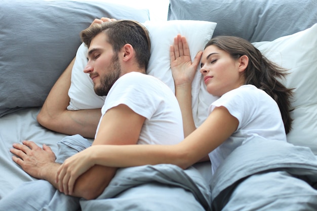 Feliz pareja durmiendo en una cómoda cama en casa.