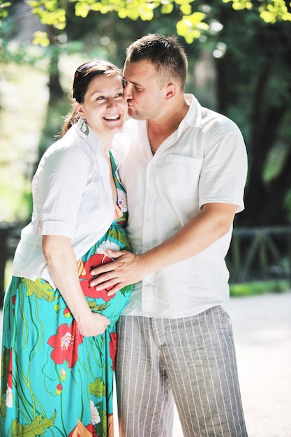 Una feliz pareja embarazada se divierte y disfruta de un momento romántico en un hermoso día soleado en el parque