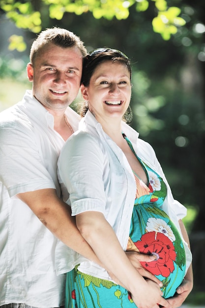 Una feliz pareja embarazada se divierte y disfruta de un momento romántico en un hermoso día soleado en el parque