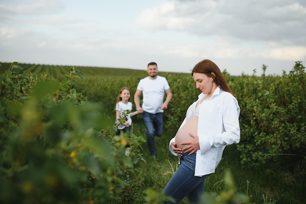 Feliz pareja embarazada con hija en la naturaleza de verano