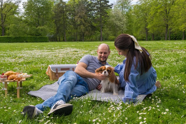 Foto una feliz pareja embarazada pasa tiempo juntos en un picnic al aire libre con un perro mascota cocker spaniel esperando un bebé amor