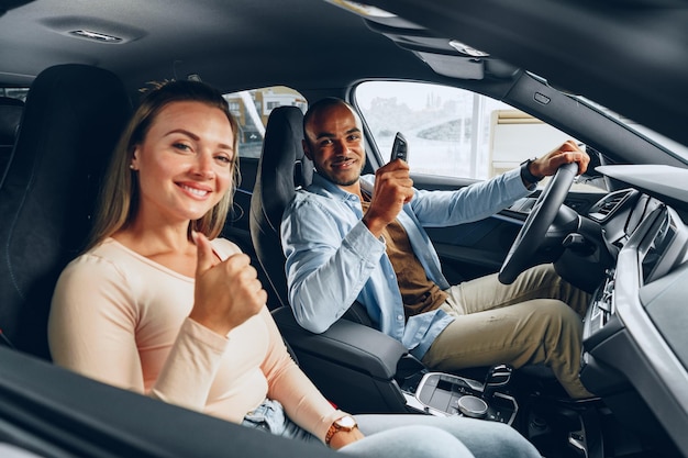 Feliz pareja emocionada comprando un coche nuevo y mostrando las llaves