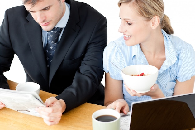 Feliz pareja de empresarios desayunando leyendo el periódico