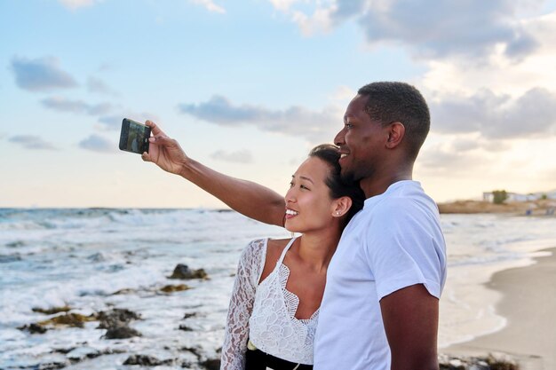 Feliz pareja enamorada tomando selfie juntos en un smartphone en la playa