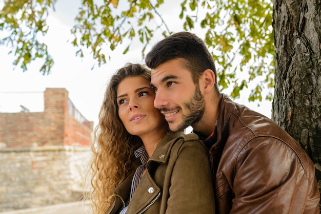 Feliz pareja de enamorados bajo el árbol