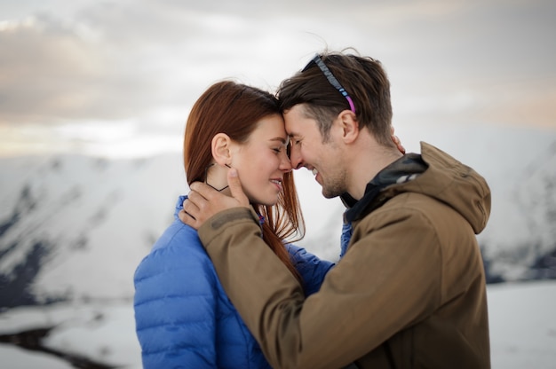 Feliz pareja de enamorados en el invierno abrazando suavemente en las montañas