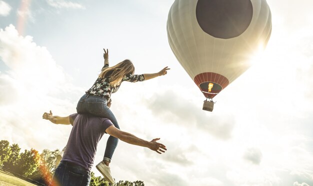 Feliz pareja de enamorados en vacaciones de luna de miel animando al globo aerostático