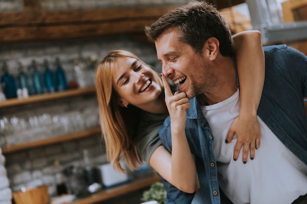 Feliz pareja encantadora joven en la cocina abrazándose unos a otros