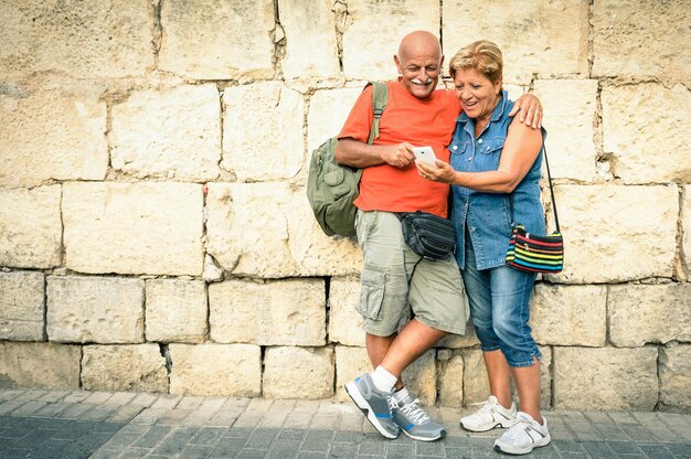 Foto una feliz pareja de estudiantes de último año de pie contra la pared