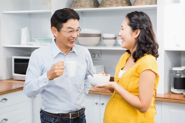 Feliz pareja expectante en la cocina desayunando