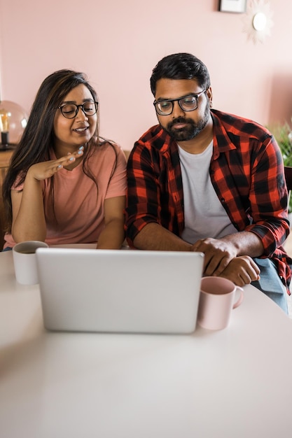 Feliz pareja de familia india acurrucarse en el escritorio hacer videollamadas a amigos usando la cámara web de la computadora portátil amando a youn