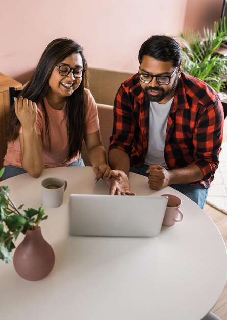 Feliz pareja de familia india acurrucarse en el escritorio hacer videollamadas a amigos usando la cámara web de la computadora portátil amando a youn