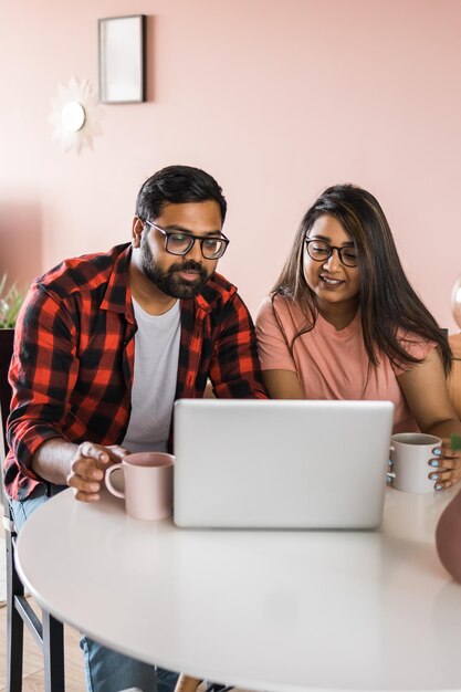 Feliz pareja de familia india acurrucarse en el escritorio hacer videollamadas a amigos usando la cámara web de la computadora portátil amando a youn