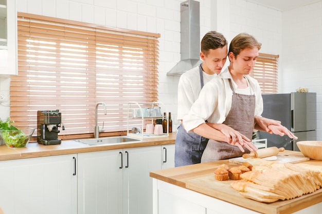 Feliz pareja gay caucásica haciendo pan juntos Una persona mezcla la harina en el frente Y otra persona mirando desde atrás en la cocina en casa Relaciones LGBT Concepto de pareja gay