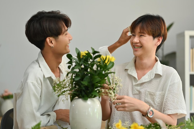 Feliz pareja gay masculina pasando tiempo juntos creando un hermoso ramo con diferentes flores en casa LGBT homosexual y amor