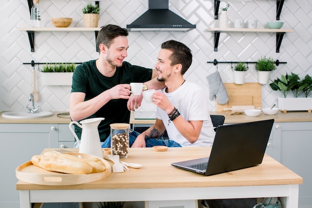 Feliz pareja gay tomando café y divirtiéndose juntos. Todos los días rutina de la vida de pareja gay en la cocina en casa. Concepto gay, vida feliz