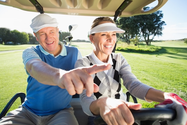 Feliz pareja de golf sentado en buggy de golf