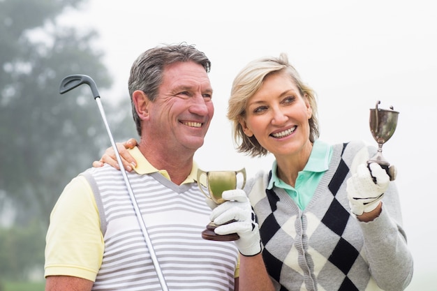 Feliz pareja de golf con trofeo