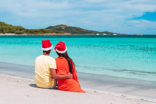 feliz pareja de gorros de santa en la playa