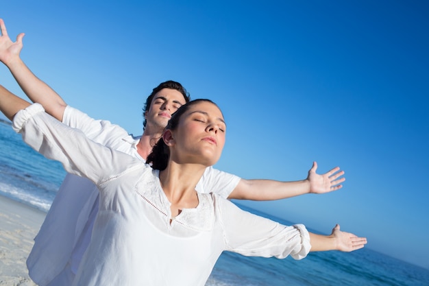 Feliz pareja haciendo yoga al lado del agua