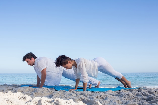 Feliz pareja haciendo yoga al lado del agua