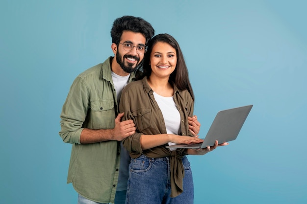 Una feliz pareja india del milenio usando una computadora portátil juntos eligiendo la compra