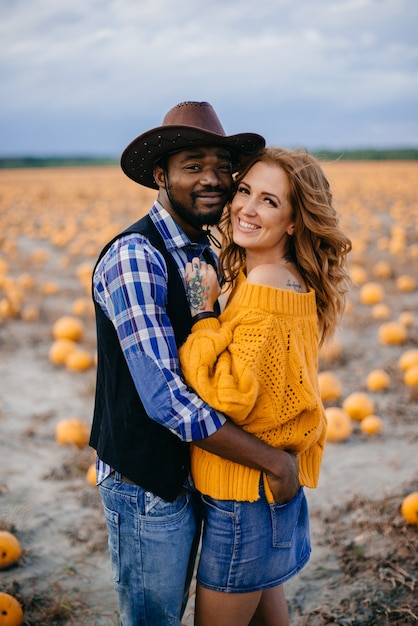 Feliz pareja interracial enamorada se encuentra en un campo de calabaza