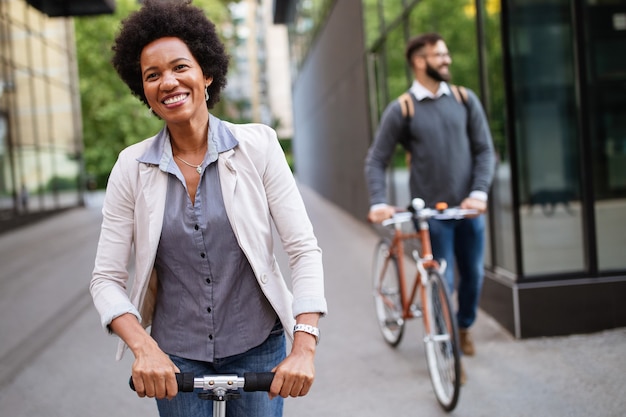 Feliz pareja interracial con scooter eléctrico, bicicleta en la ciudad. Concepto de energía ecológica verde con cero emisiones.