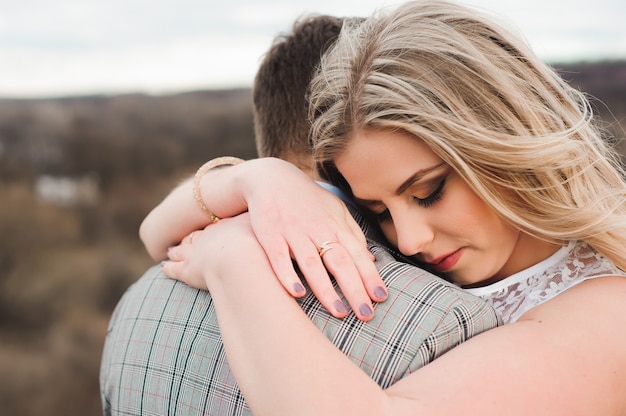 Foto feliz pareja joven abrazando al borde de la montaña