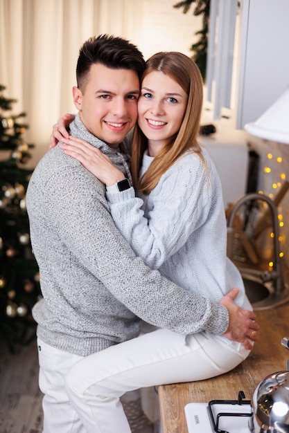 Feliz pareja joven abrazándose en la cocina decorada para el año nuevo Interior de año nuevo en la cocina Cocina navideña