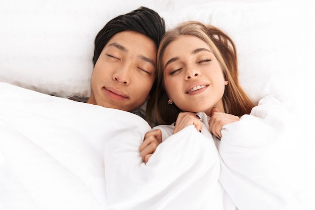 Feliz, pareja joven, acostado, en cama, ojos cerrados