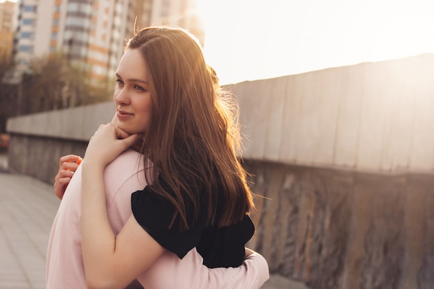 Feliz pareja joven de amigos, adolescentes, estudiantes abrazándose en la calle de la ciudad