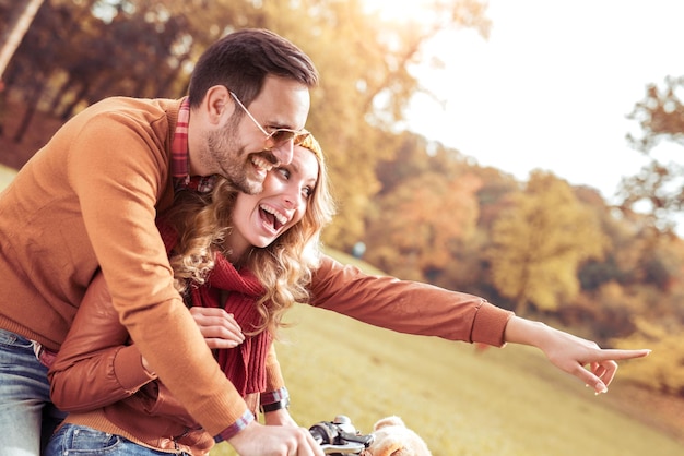 Feliz pareja joven andar en bicicleta en un día de otoño