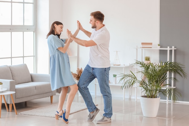 Feliz pareja joven bailando en casa